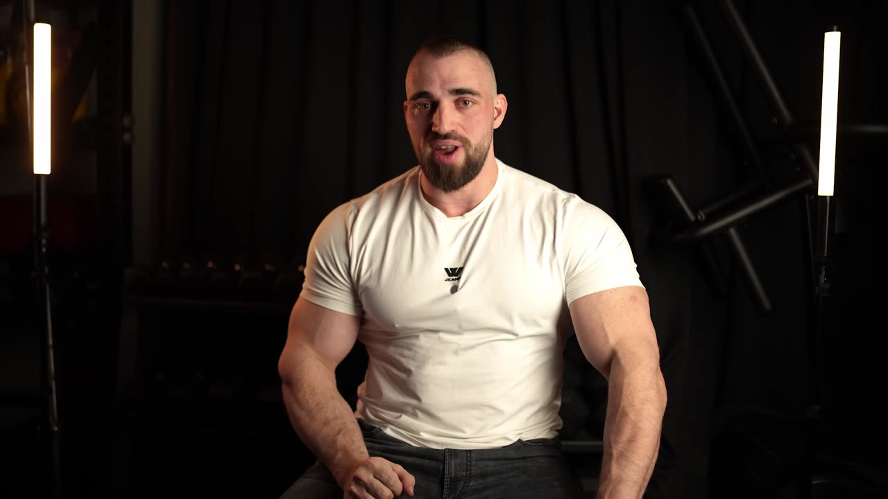 Dani in a white T-shirt, lit against black with vertical tube lights