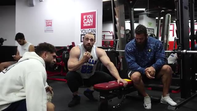 Dani coaching a leg workout on a red bench in a busy gym